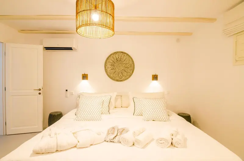 Une chambre lumineuse avec un grand lit recouvert de linge blanc et de coussins.