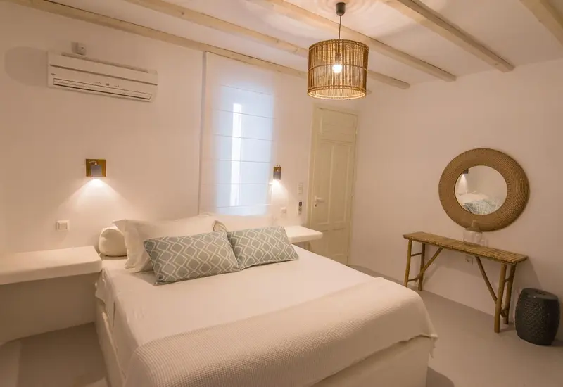 Une chambre lumineuse avec un lit blanc et un décor minimaliste.