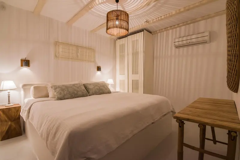 Une chambre lumineuse avec un lit double et des meubles en bois.