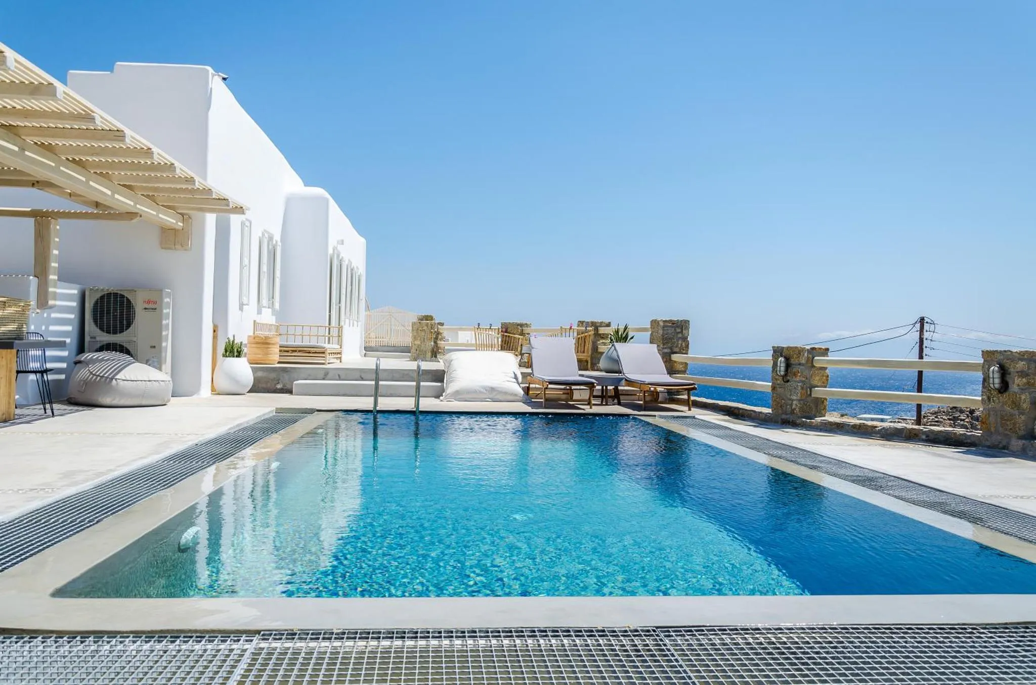 Terrasse avec piscine et mobilier de détente face à la mer.