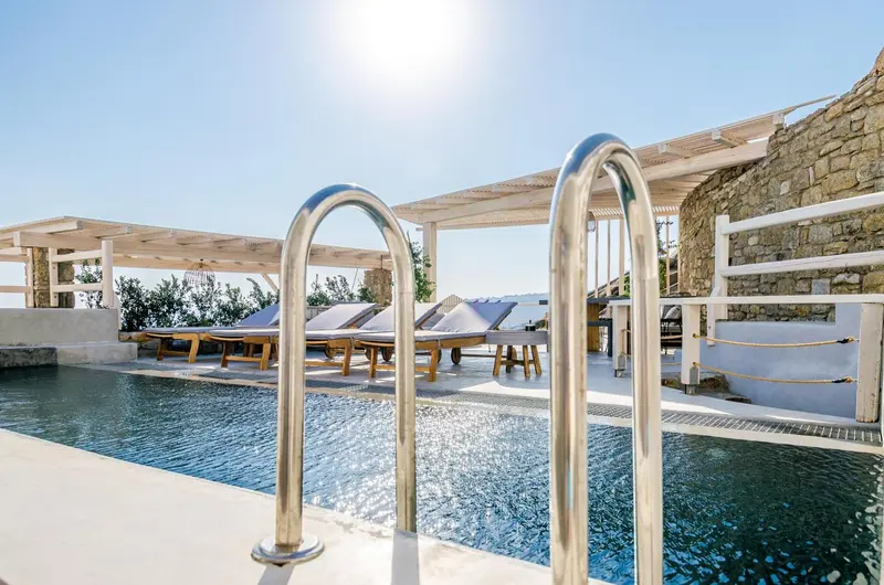 Terrasse avec piscine et chaises longues ensoleillées.