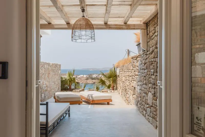 Terrasse ombragée donnant sur un paysage côtier ensoleillé.