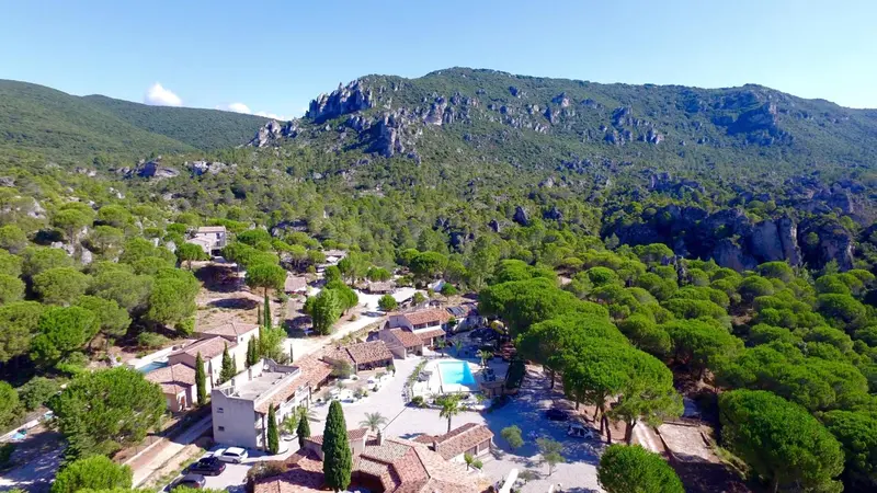 Vue aérienne d'un ensemble de bâtiments entourés de végétation et dominant un paysage montagneux.