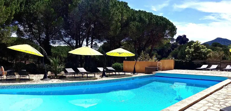 Transats bleus et parasols jaunes disposés autour d'une piscine turquoise.