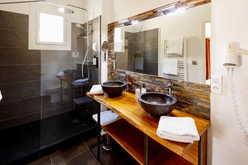 Une salle de bain moderne avec une douche à l'italienne et des vasques en pierre.