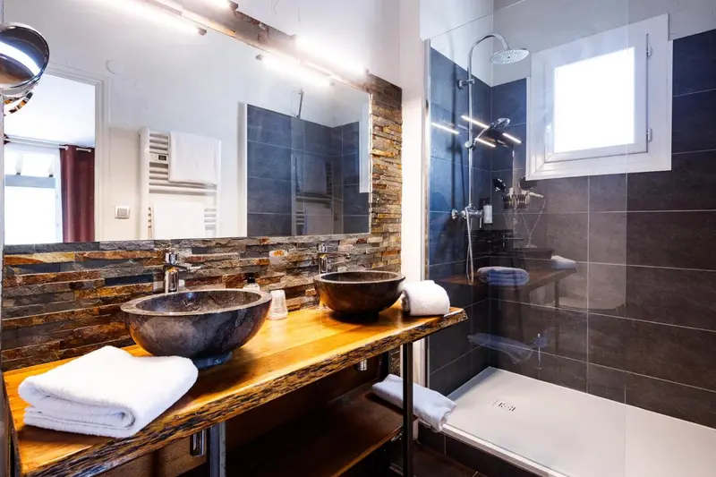 Une salle de bain moderne avec deux vasques en pierre et une douche à l'italienne.