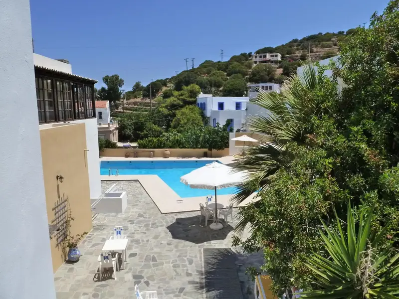Vue sur une piscine ensoleillée avec des transats et des parasols.