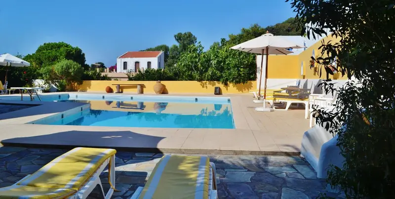 Transats blancs et parasols près d'une piscine ensoleillée.