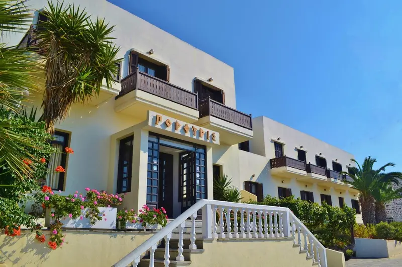 Façade d'un bâtiment blanc orné de balcons et de végétation tropicale.