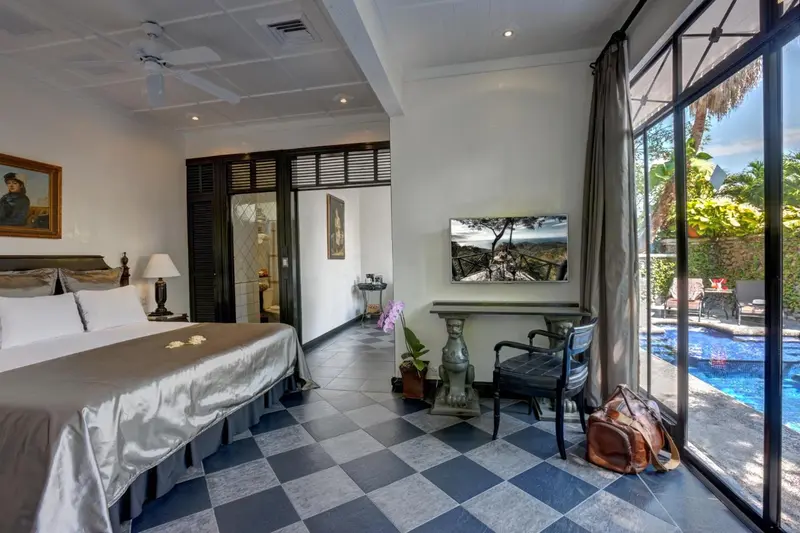 Chambre spacieuse avec un lit king-size et un accès à une piscine extérieure.