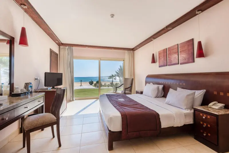 Chambre lumineuse avec un grand lit et vue sur la mer.