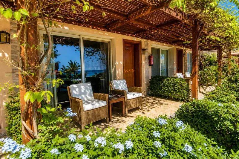 Terrasse ombragée avec mobilier d'extérieur devant des chambres d'hôtel.