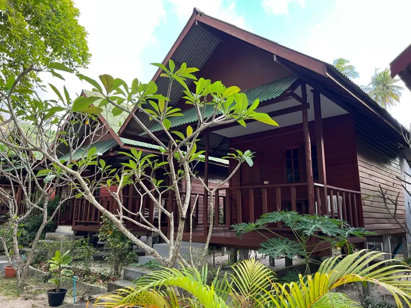 Bâtiment en bois brun avec des terrasses et une végétation tropicale.