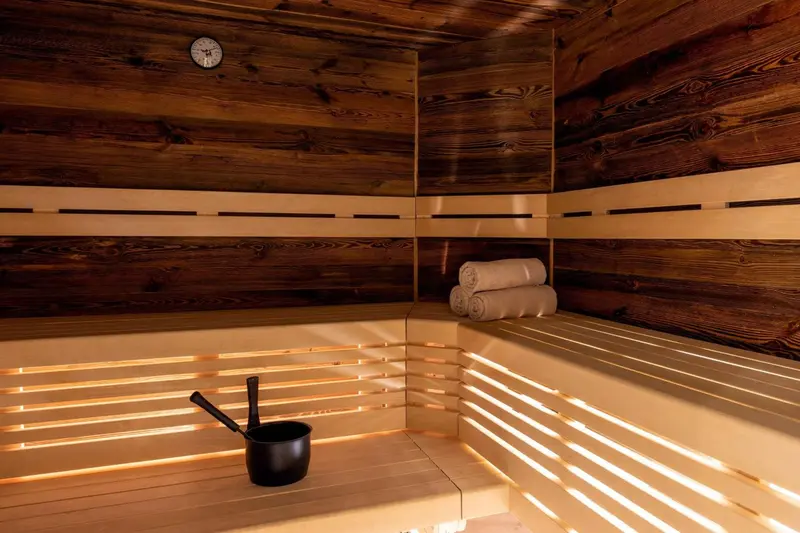 Intérieur chaleureux d'un sauna en bois avec des serviettes enroulées et un seau.
