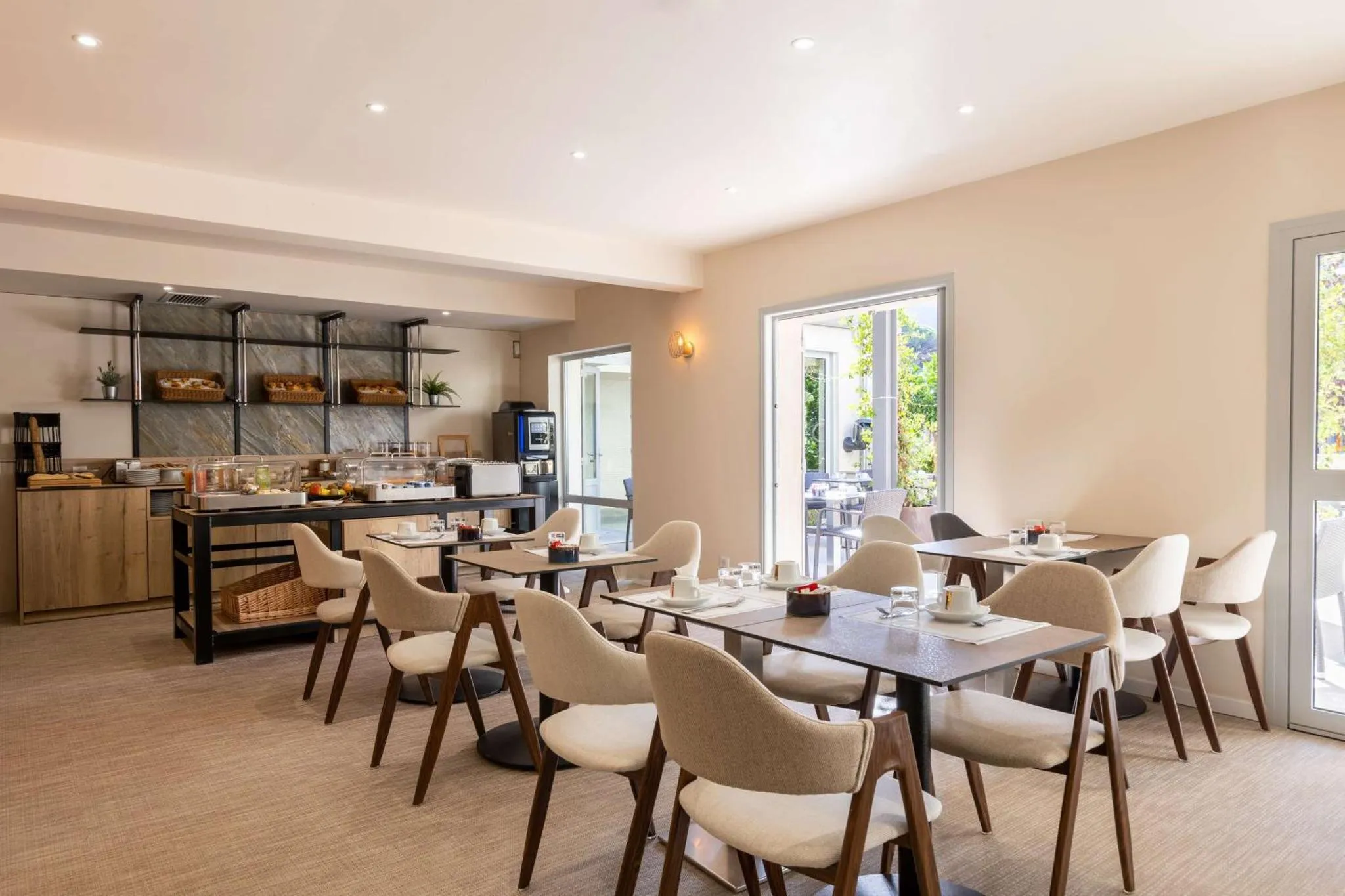 Une salle lumineuse avec des tables et des chaises pour le petit-déjeuner.