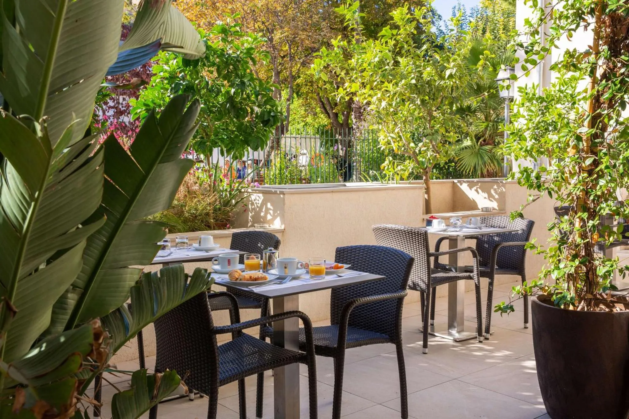 Tables de restaurant en terrasse avec des couverts et des boissons.