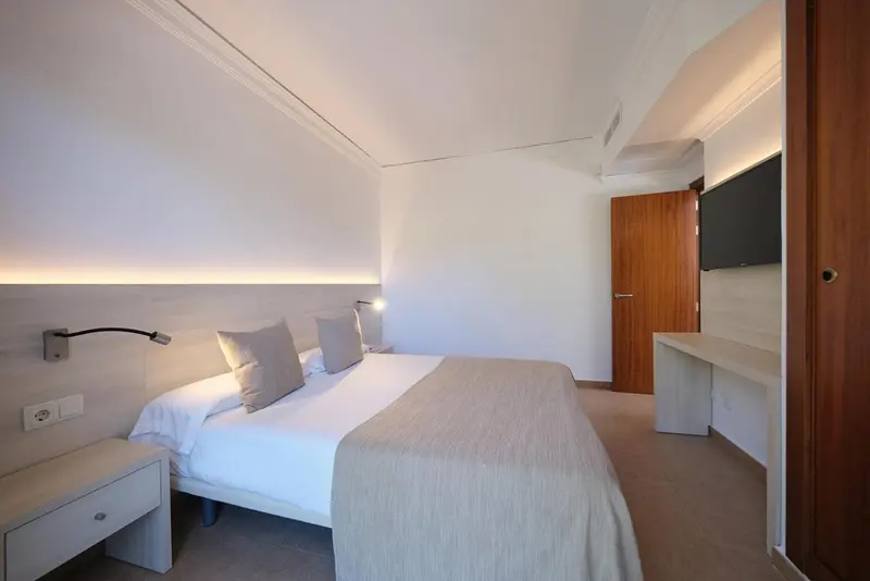 Une chambre lumineuse avec un lit double et un bureau.