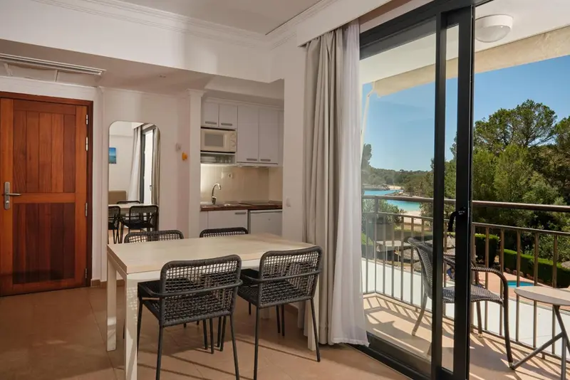 Une salle à manger lumineuse s'ouvre sur une terrasse avec vue sur la végétation et la mer.