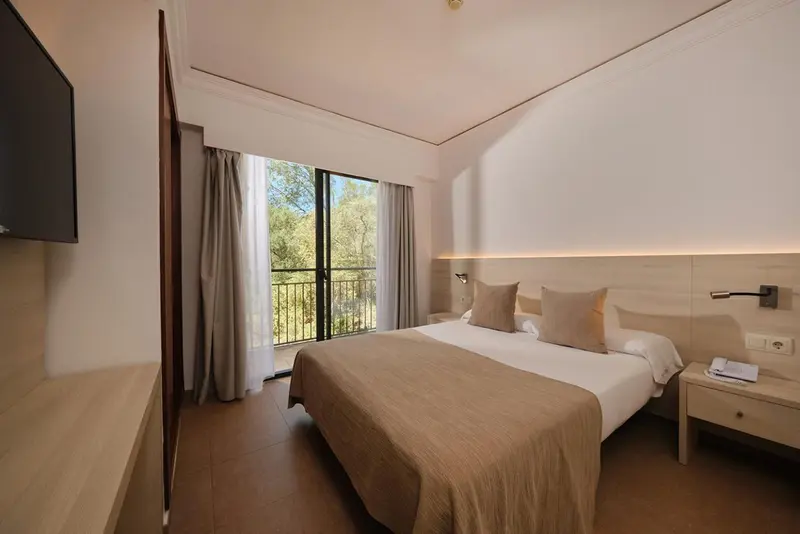 Une chambre lumineuse avec un grand lit et un accès à un balcon.