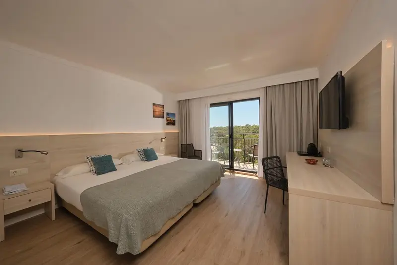 Chambre lumineuse avec un grand lit et un bureau.