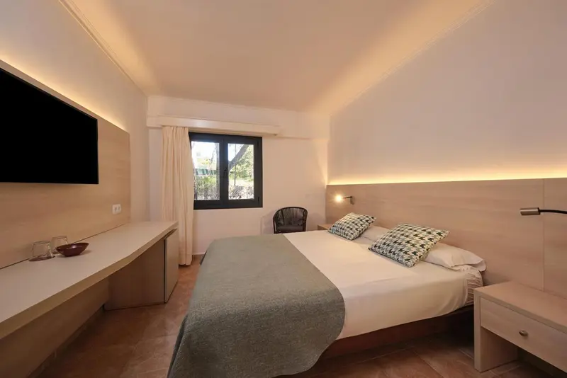 Une chambre lumineuse avec un lit double et un bureau.