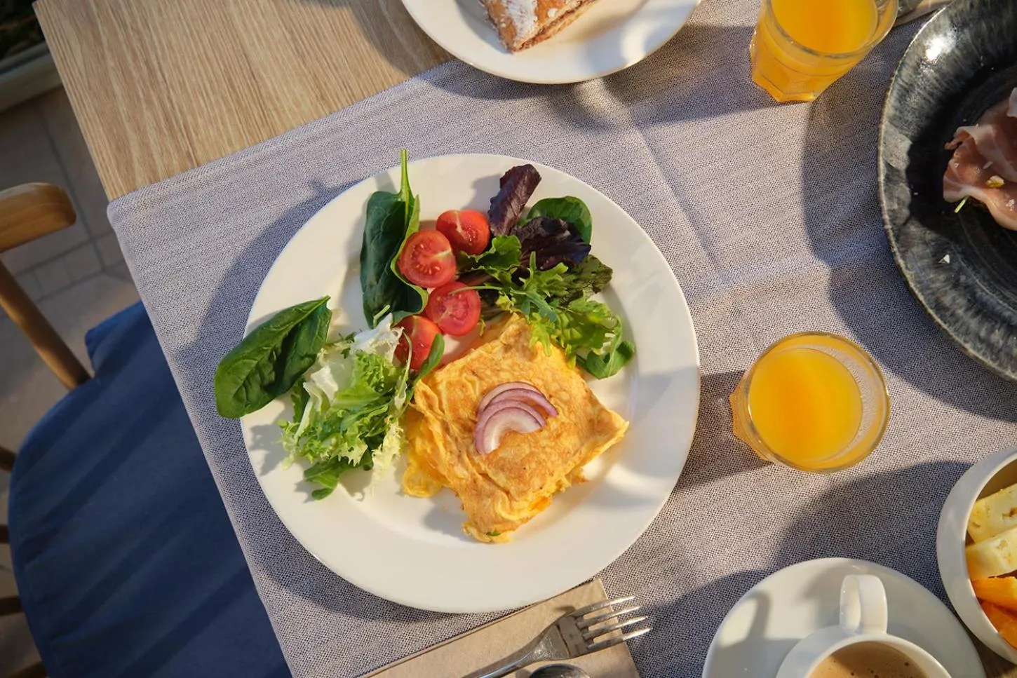 Une table est dressée avec des assiettes garnies de nourriture et des verres de jus d'orange.
