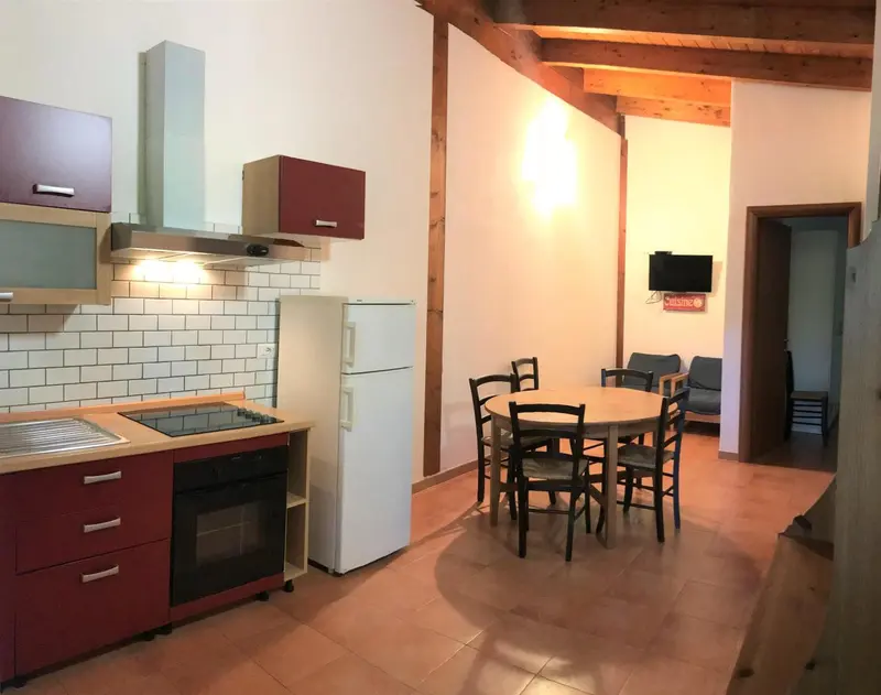 Une cuisine ouverte sur un coin repas avec table ronde et chaises.