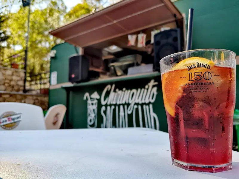 Un verre de boisson fraîche sur une table en extérieur, devant un bar.