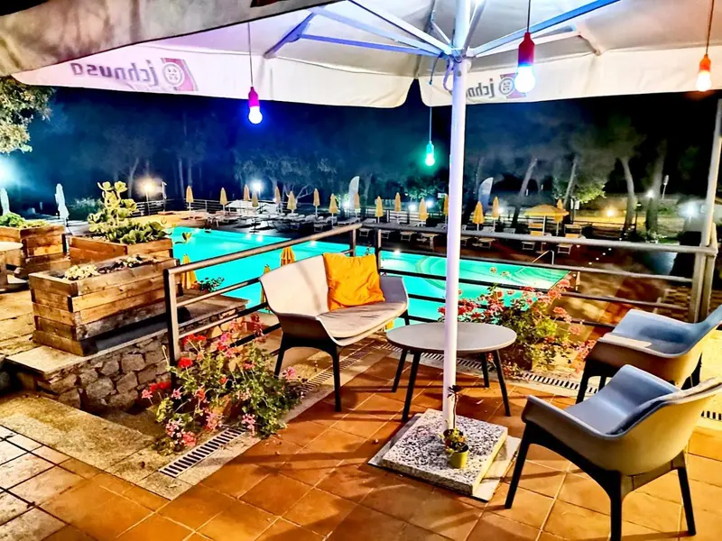 Terrasse avec mobilier d'extérieur et piscine éclairée en soirée.
