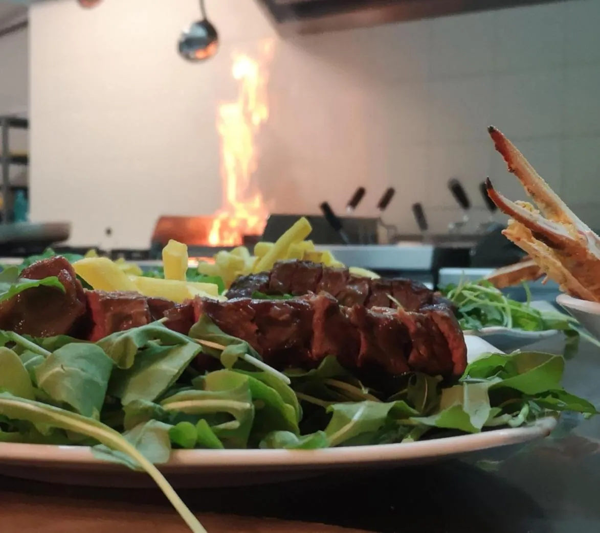 Une assiette de viande grillée accompagnée d'une salade verte est mise en valeur au premier plan.
