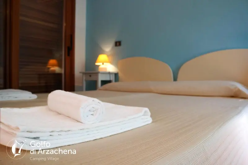 Une chambre lumineuse avec un lit fait et des serviettes pliées sur le couvre-lit.