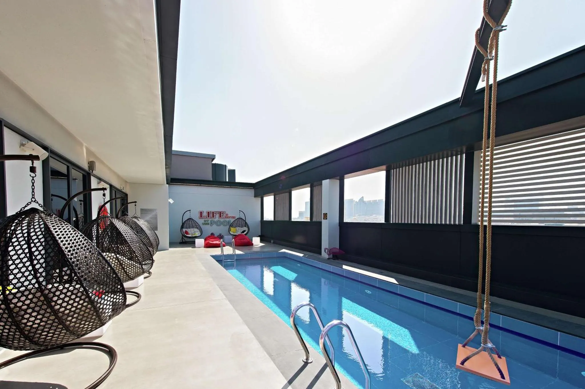Une piscine rectangulaire avec des chaises suspendues sur le côté.