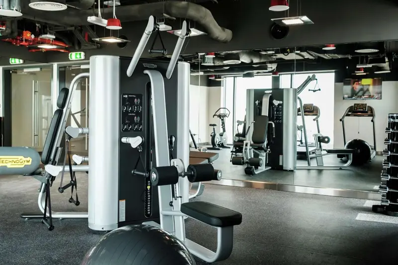 Une salle de sport moderne avec des équipements de musculation et des miroirs.