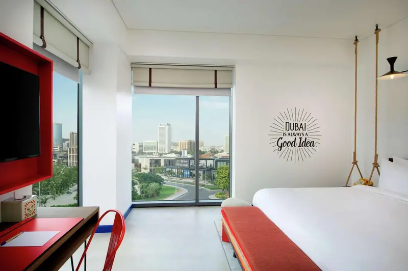 Une chambre lumineuse avec un grand lit et une vue sur la ville.