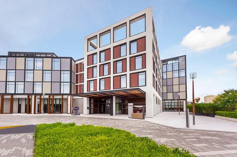 Façade moderne d'un bâtiment avec un accès couvert et un parterre verdoyant.