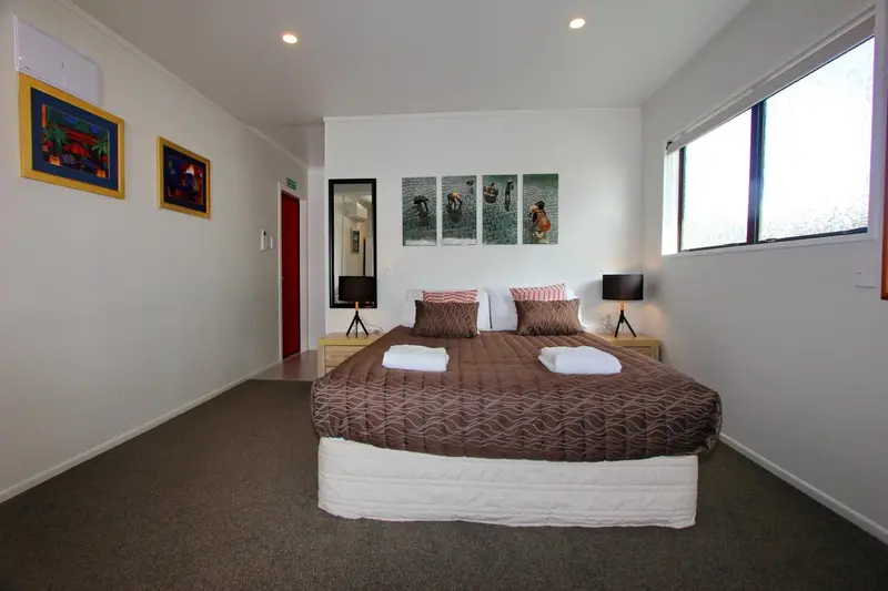 Une chambre lumineuse avec un grand lit recouvert d'une courtepointe marron.