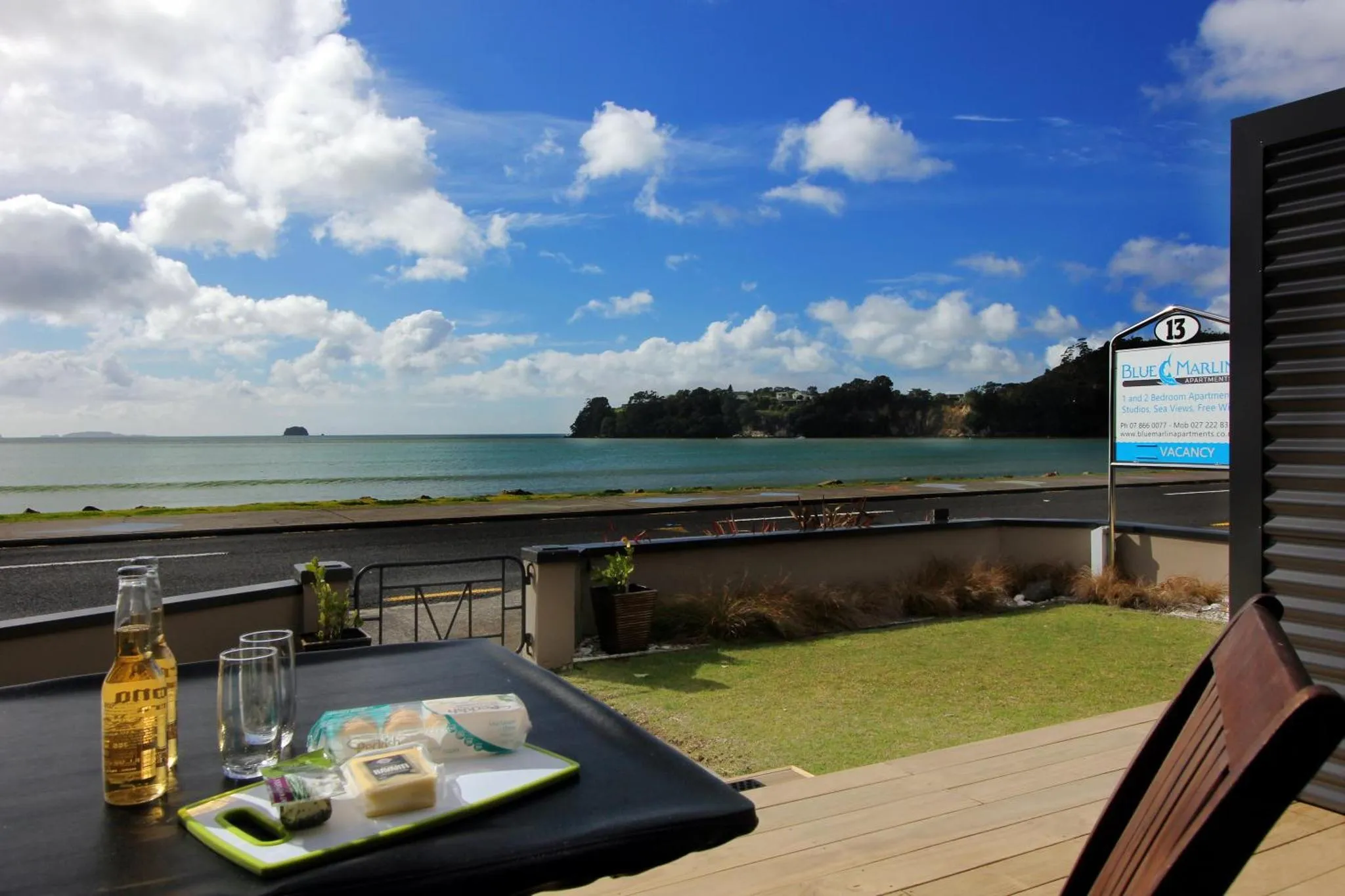 Une table avec des boissons et des collations sur une terrasse ensoleillée avec vue sur la mer.