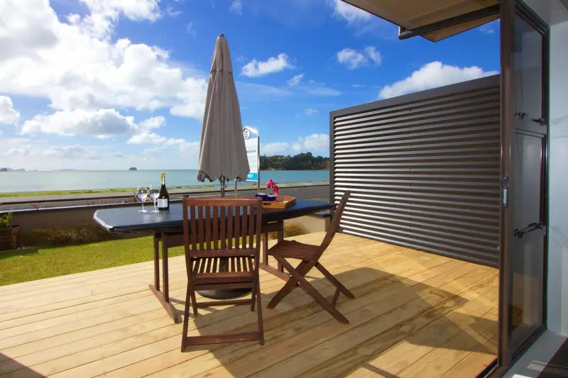 Une table et des chaises en bois sont disposées sur une terrasse en bois avec vue sur la mer.