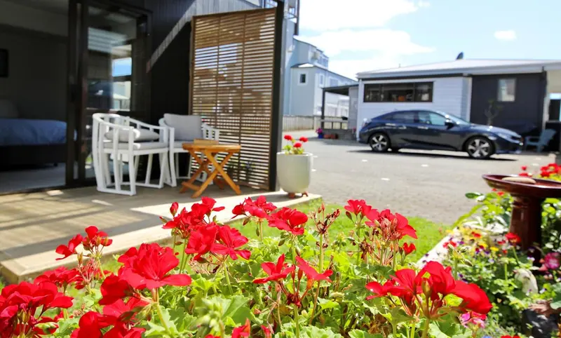 Terrasse aménagée avec mobilier blanc et fleurs colorées devant des bâtiments.