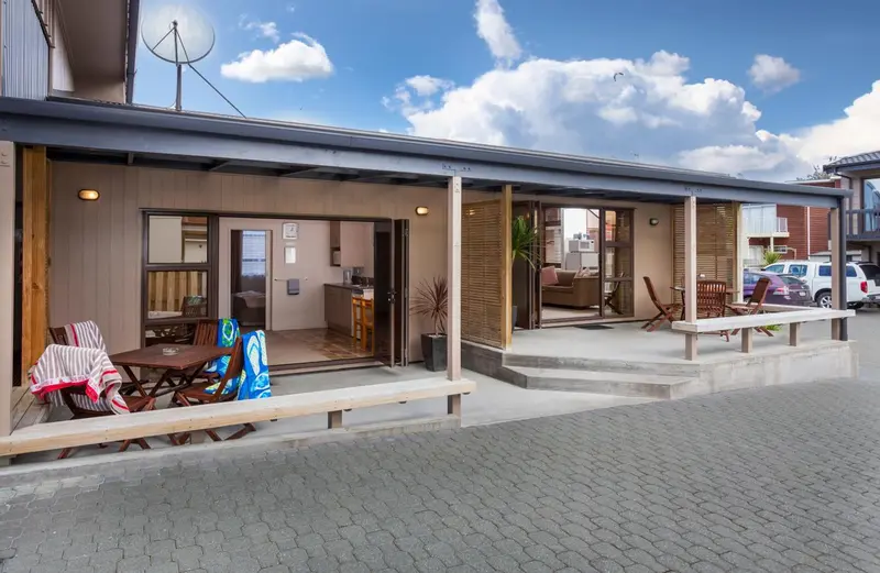 Terrasse ombragée donnant sur des logements ouverts sur l'extérieur.