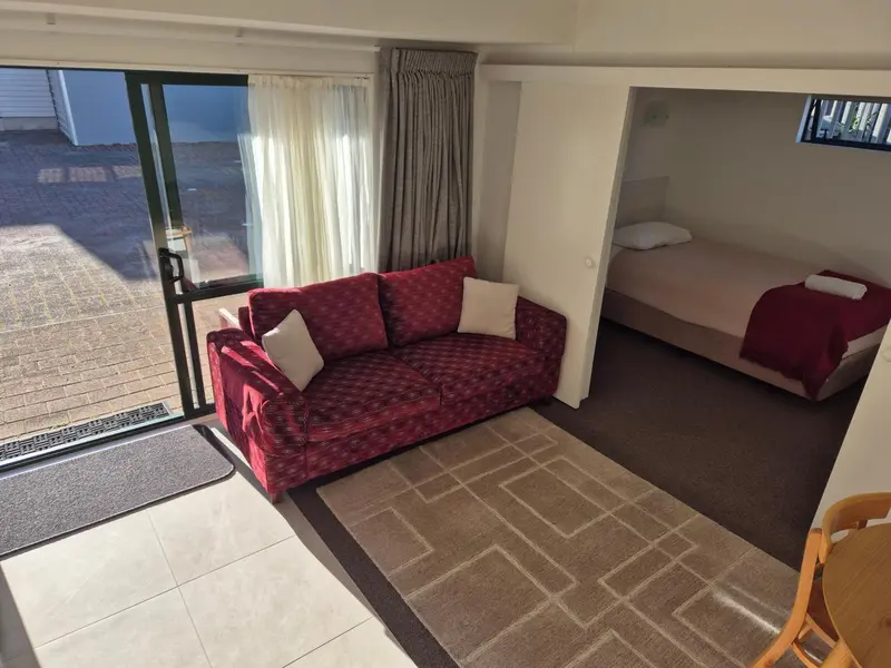 Espace de vie avec canapé rouge et chambre attenante.