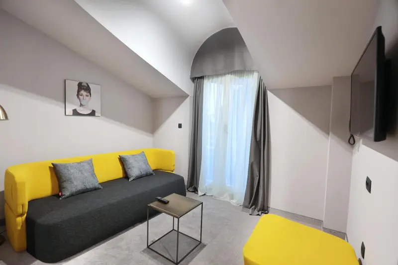 Espace de détente intérieur avec canapé jaune et coussins gris.