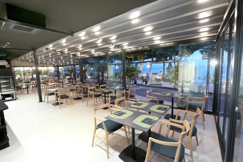 Une salle à manger lumineuse avec de grandes baies vitrées donnant sur une terrasse.
