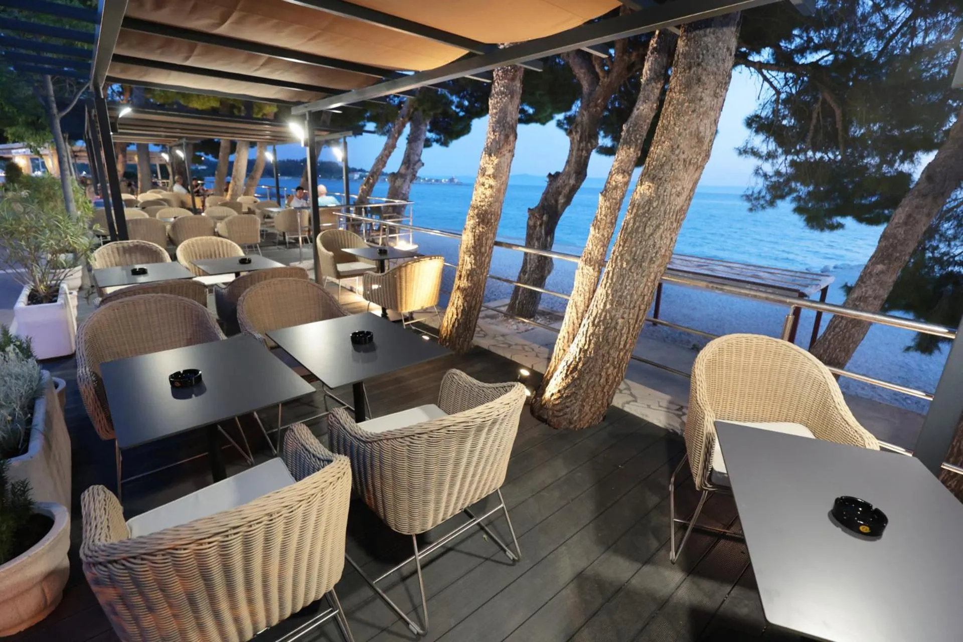 Terrasse de restaurant avec tables et chaises en osier face à la mer.