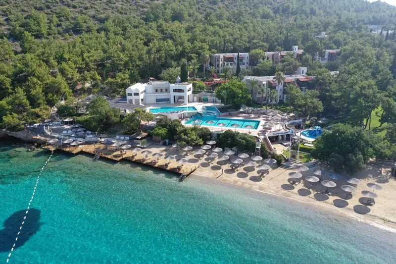 Vue aérienne d'un complexe hôtelier blanc avec piscine et plage.