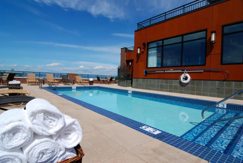 Une piscine rectangulaire avec des transats et des serviettes enroulées au premier plan.