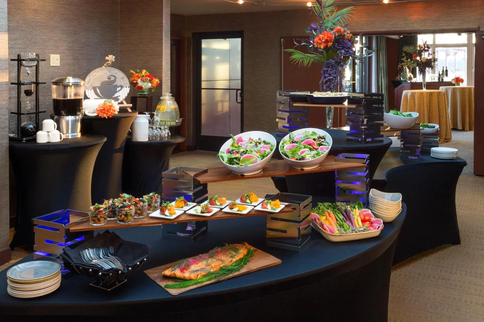 Un buffet propose une variété de plats et de salades dans une salle lumineuse.