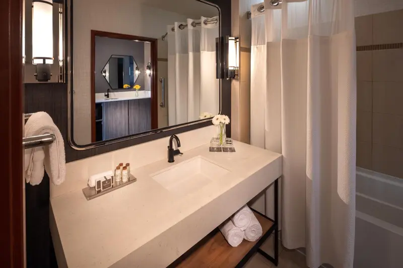 Une salle de bain moderne avec un grand miroir et des serviettes blanches.