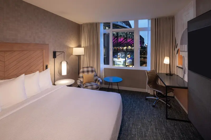 Chambre avec un grand lit et un bureau près d'une fenêtre.