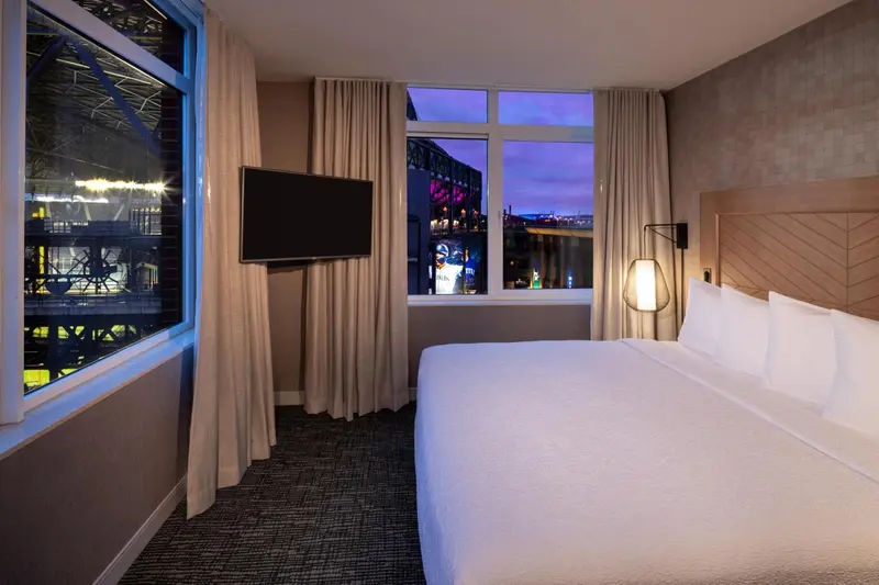 Une chambre lumineuse avec un grand lit et une vue sur la ville.